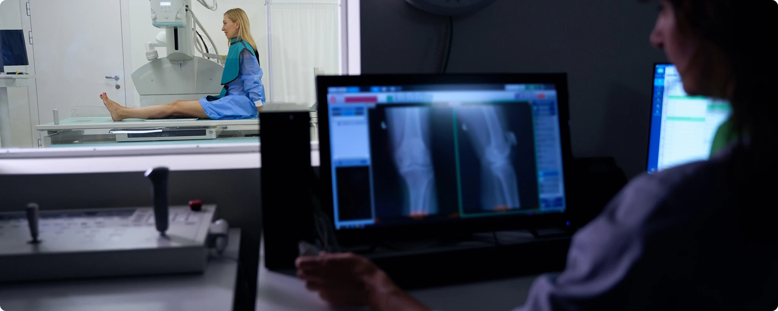 Patient receiving leg X-ray, technician reviewing images.